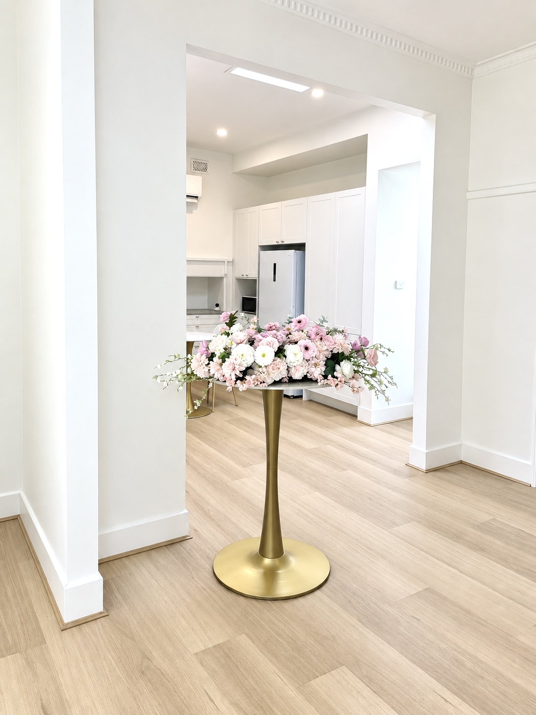 The Regenerate clinic interior, with a floral arrangement on a gold stand and the kitchen beyond